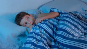 Niño inquieto en la cama experimentando dificultades para dormir